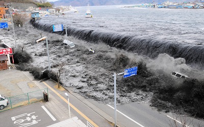 Numerical Modeling of Tsunami-Like Solitary Wave Impinging and Overtopping a Seawall through SPH Schemes by Considering the Effect of Entrapped Air